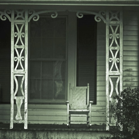 Old-fashioned photo of a rocking chair on an ornate porch